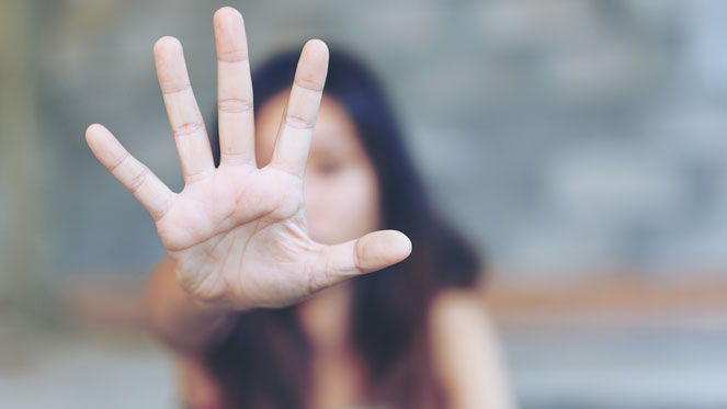 Woman with her hand opened blocking her face